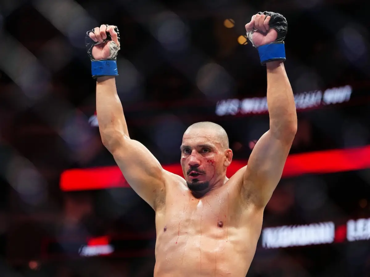 Lutador brasileiro Carlos Leal de pé no centro do octógono, com os braços abertos e erguidos em comemoração após o anúncio da vitória por decisão unânime sobre Chidi Njokuani em Houston