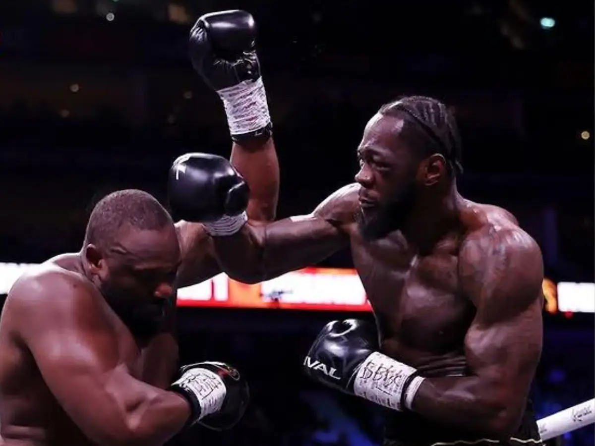 Fotografia capturada durante o combate entre Deontay Wilder (à direita) e Derek Chisora (à esquerda) na O2 Arena em Londres; o pugilista norte-americano aparece com a mão direita levantada logo após conectar um golpe no adversário britânico